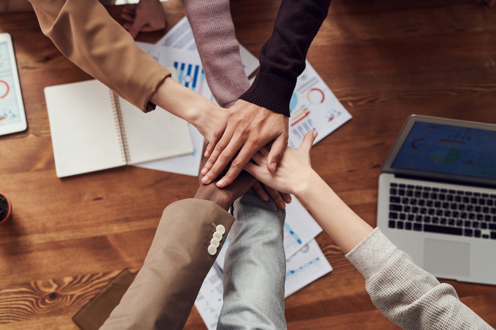 Hands joined together around a table, representing mutual support
